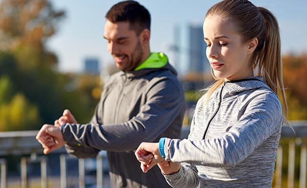 Two runners looking at their fitness activity trackers
