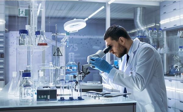 Man in lab looking through microscope